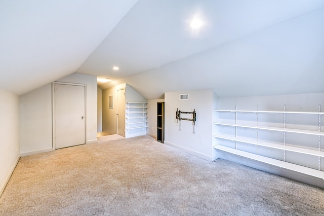 bonus room with vaulted ceiling and light colored carpet