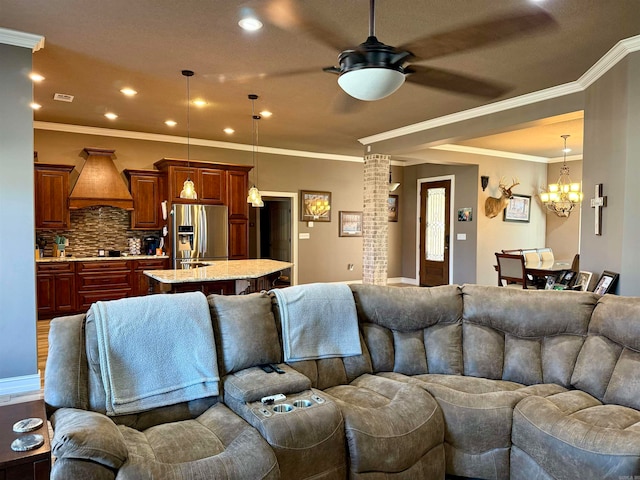 living room featuring ceiling fan with notable chandelier and crown molding