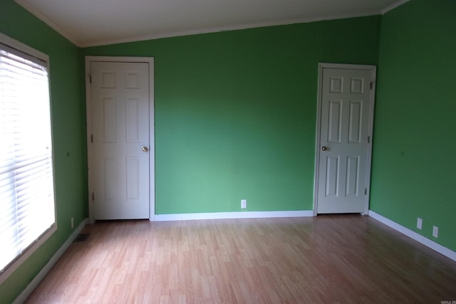 unfurnished room with light wood-type flooring, plenty of natural light, crown molding, and lofted ceiling