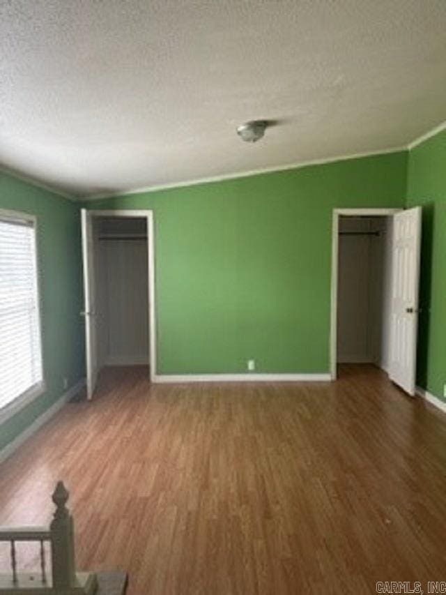 unfurnished bedroom featuring hardwood / wood-style flooring, ornamental molding, and a textured ceiling