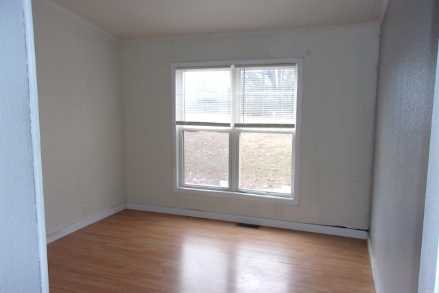 spare room featuring light wood-type flooring and ornamental molding