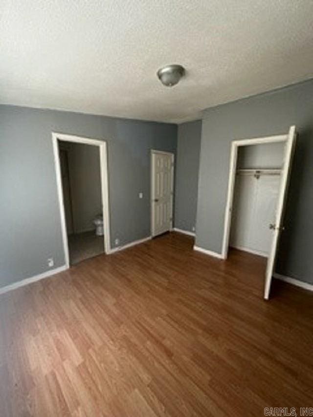 unfurnished bedroom featuring a textured ceiling and dark wood-type flooring