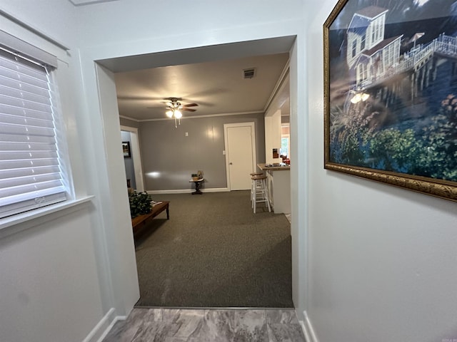 hallway with crown molding, visible vents, and baseboards