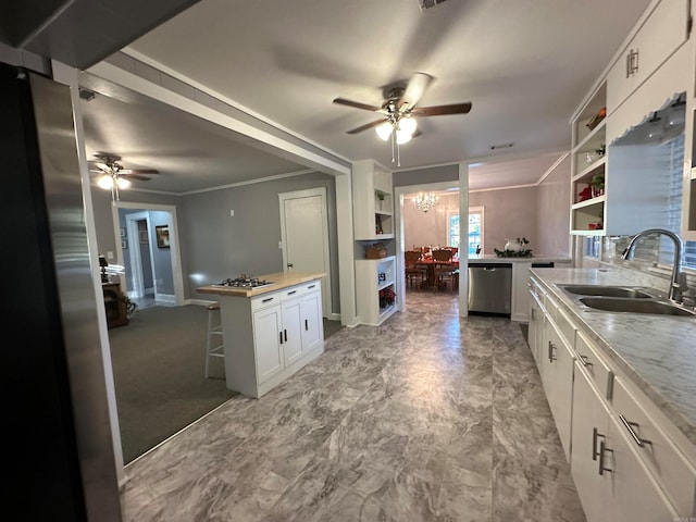 kitchen featuring sink, ceiling fan with notable chandelier, white cabinets, stainless steel appliances, and crown molding