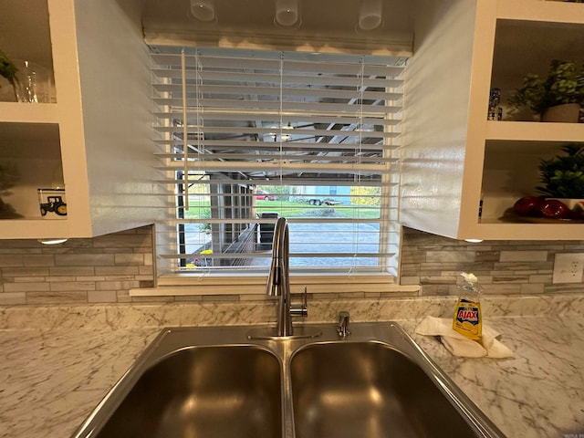 details featuring light stone countertops, backsplash, and sink