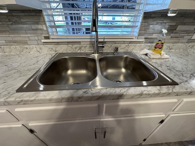 room details featuring light countertops, decorative backsplash, and a sink