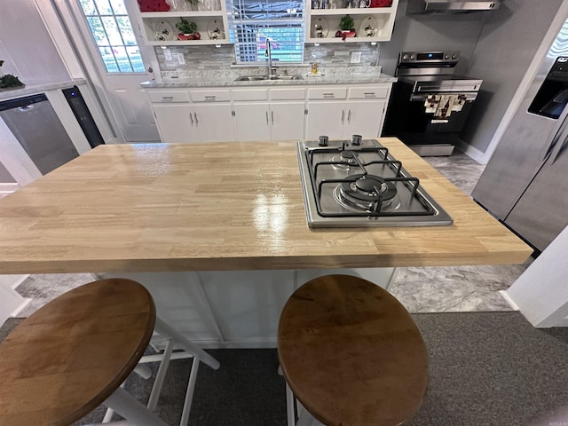 kitchen with white cabinets, open shelves, appliances with stainless steel finishes, and a sink