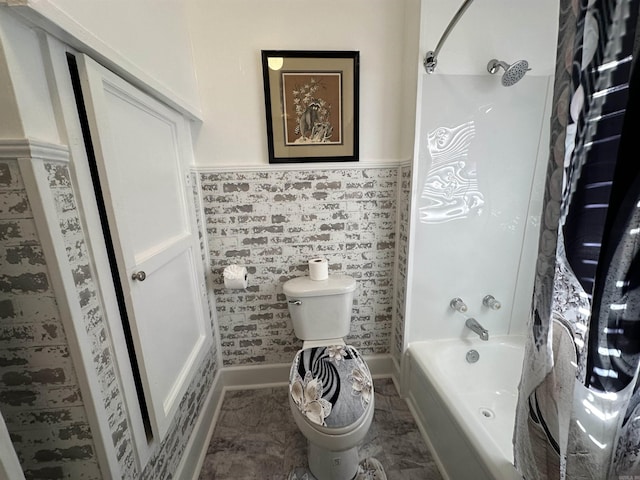 bathroom featuring marble finish floor, toilet, a wainscoted wall, and bathtub / shower combination
