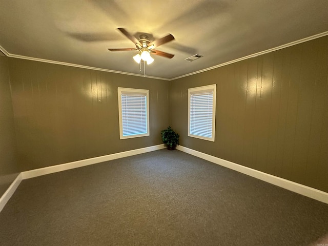 carpeted empty room with wood walls, ceiling fan, and crown molding