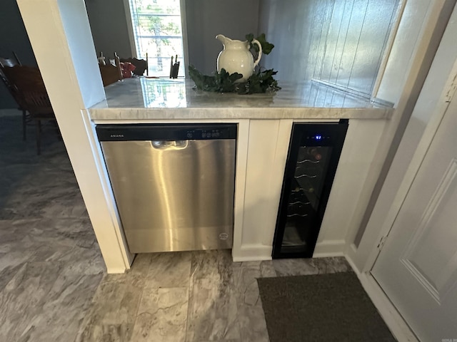 details featuring beverage cooler, stainless steel dishwasher, white cabinets, and light countertops