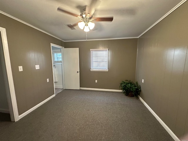 unfurnished room with ornamental molding, dark colored carpet, and ceiling fan