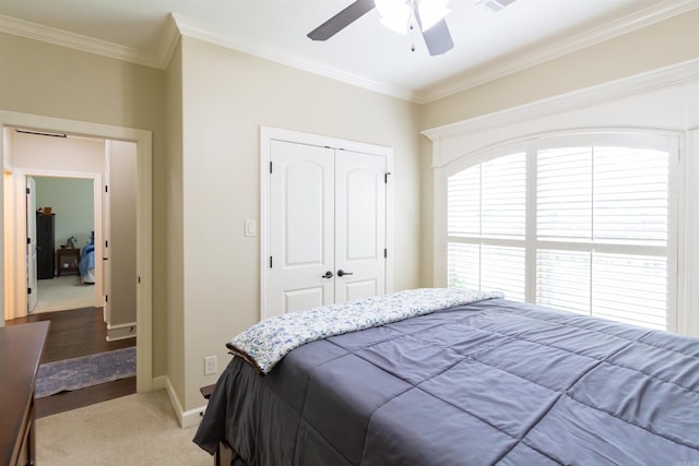 bedroom with ceiling fan, hardwood / wood-style flooring, a closet, and ornamental molding