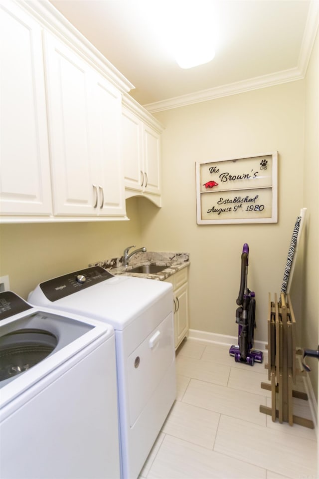 washroom with ornamental molding, cabinets, sink, and washing machine and clothes dryer