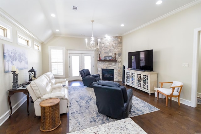 living room with dark hardwood / wood-style flooring, lofted ceiling, an inviting chandelier, a stone fireplace, and ornamental molding