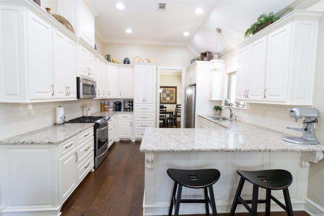 kitchen with stainless steel appliances, white cabinets, vaulted ceiling, and dark hardwood / wood-style flooring