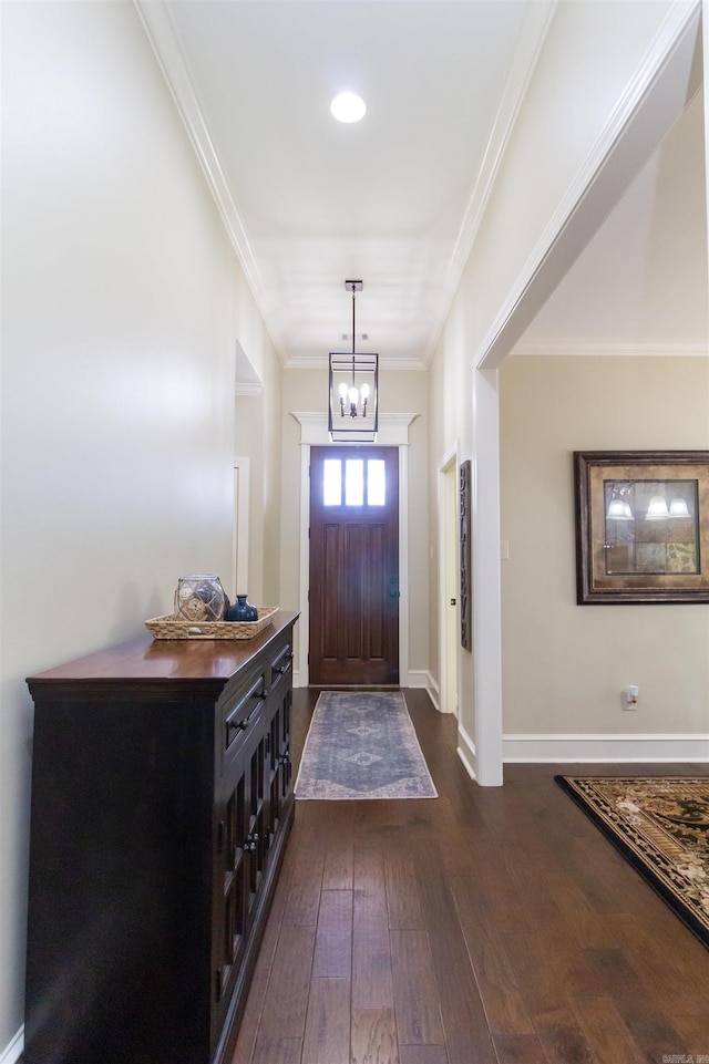 foyer entrance featuring ornamental molding, a chandelier, and dark wood-type flooring