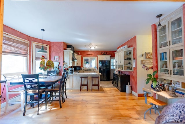 kitchen with a kitchen breakfast bar, light hardwood / wood-style flooring, black fridge, and decorative light fixtures