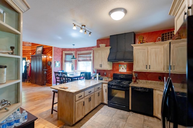 kitchen with light stone counters, wood walls, kitchen peninsula, and black appliances