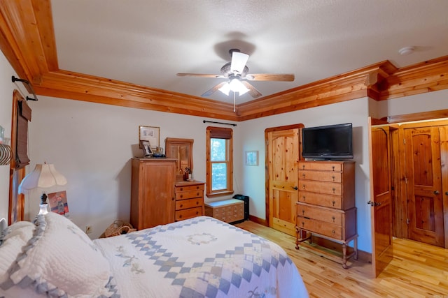 bedroom featuring light wood-type flooring, crown molding, a textured ceiling, and ceiling fan