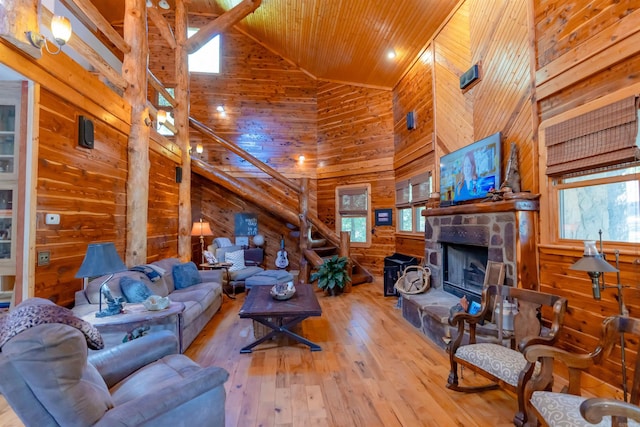 living room featuring wood-type flooring, wood walls, high vaulted ceiling, a stone fireplace, and wooden ceiling