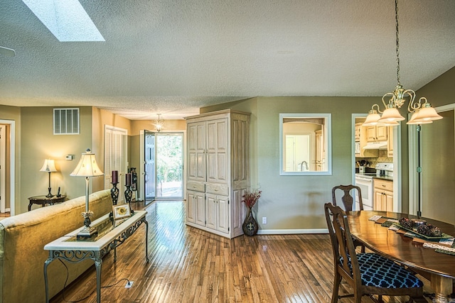 dining area with a textured ceiling, hardwood / wood-style floors, and a skylight