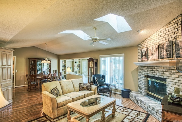 living room with vaulted ceiling, a brick fireplace, a textured ceiling, ceiling fan, and hardwood / wood-style floors