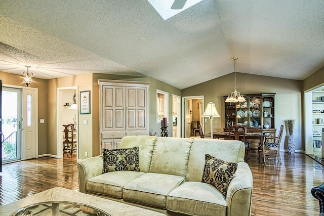 living room featuring a chandelier, a textured ceiling, lofted ceiling with skylight, and dark wood-type flooring