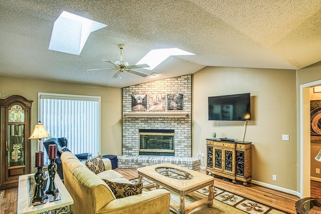 living room featuring a textured ceiling, vaulted ceiling, a brick fireplace, hardwood / wood-style floors, and ceiling fan