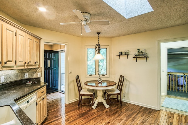 dining space with a textured ceiling, a skylight, ceiling fan, and dark hardwood / wood-style flooring