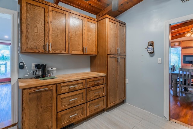 kitchen with vaulted ceiling with beams, light hardwood / wood-style flooring, and wooden ceiling