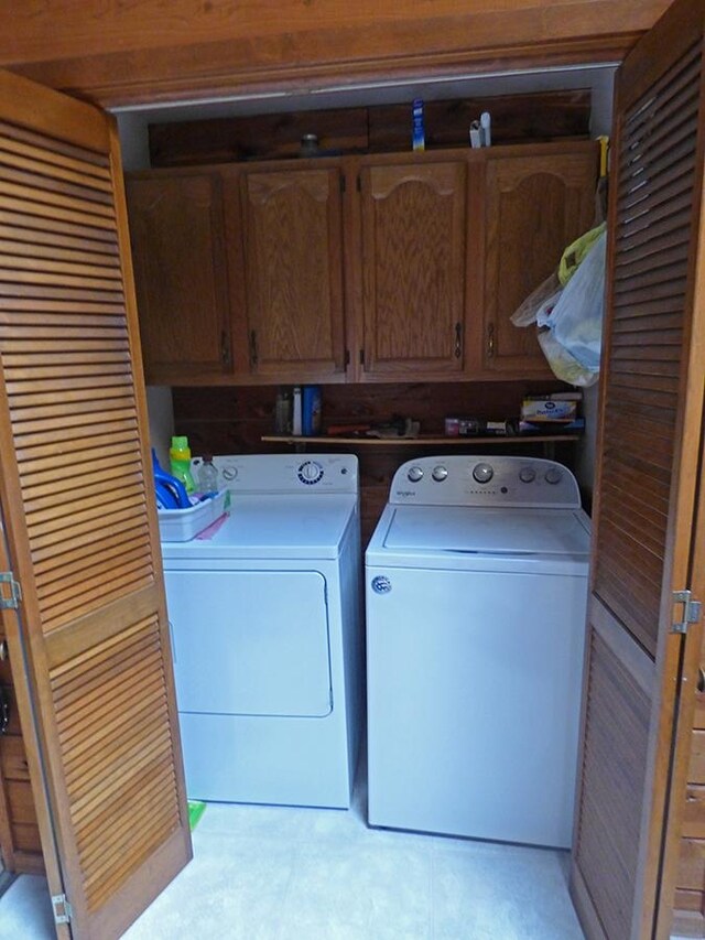 laundry room with washing machine and clothes dryer and cabinets