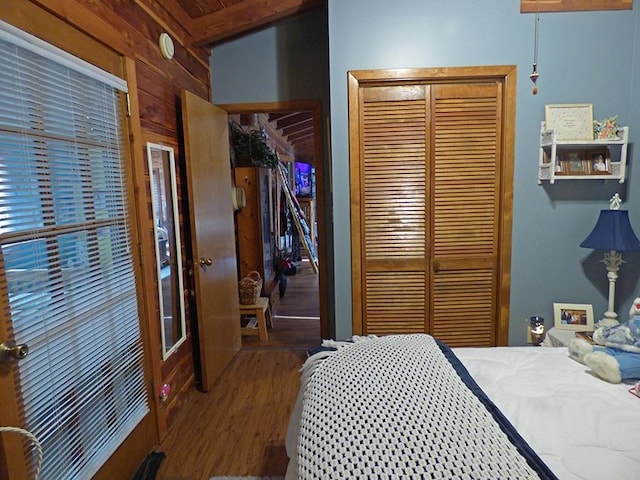 bedroom featuring beam ceiling, wood walls, a closet, and hardwood / wood-style floors