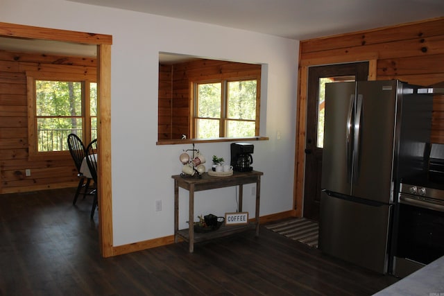 kitchen featuring wood walls, dark hardwood / wood-style floors, a healthy amount of sunlight, and stainless steel fridge