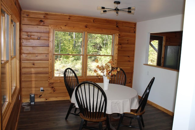 dining space with wood walls, plenty of natural light, and dark hardwood / wood-style flooring