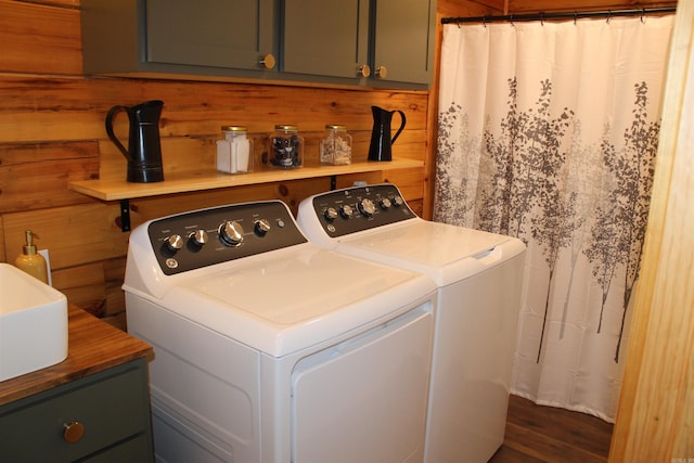 washroom featuring cabinets, wooden walls, dark hardwood / wood-style flooring, and washing machine and clothes dryer