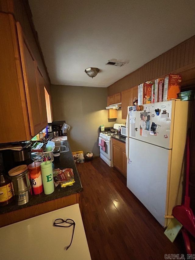 kitchen featuring sink, dark wood-type flooring, and white appliances