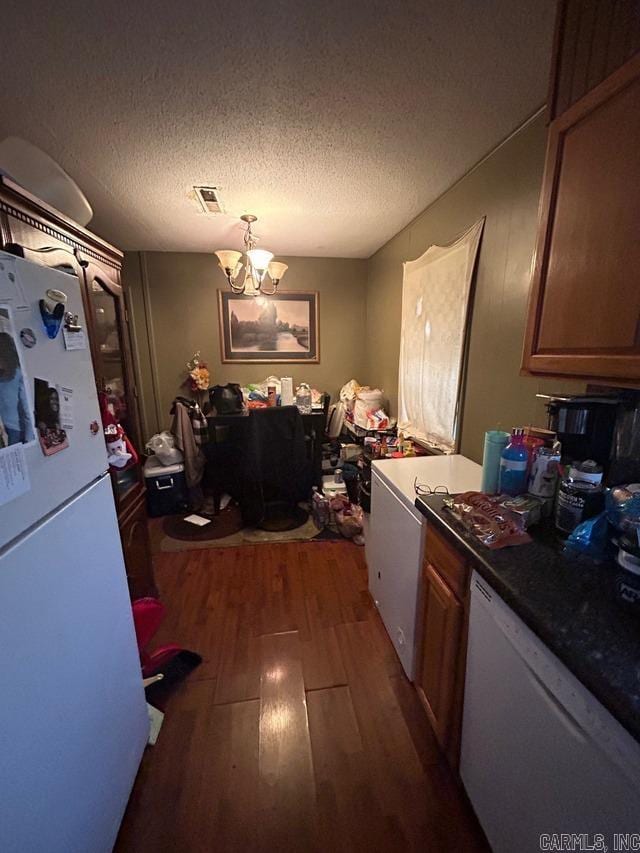 kitchen featuring a textured ceiling, white appliances, dark wood-type flooring, and a chandelier