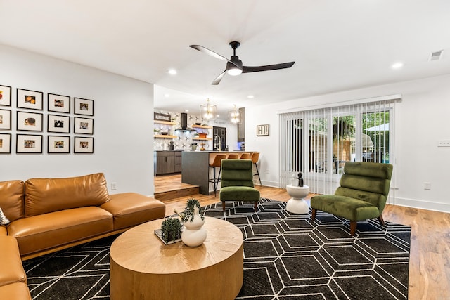 living room with ceiling fan with notable chandelier and hardwood / wood-style floors