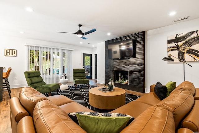 living room with ceiling fan, hardwood / wood-style flooring, and a fireplace