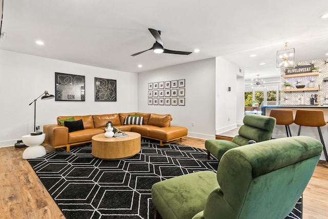 living room with wood-type flooring and ceiling fan with notable chandelier