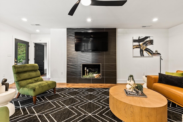 living room featuring ceiling fan, a fireplace, and hardwood / wood-style floors