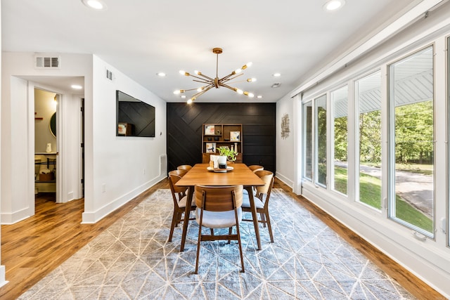 dining room featuring an inviting chandelier, wood-type flooring, and wooden walls