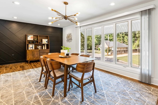 dining space featuring wooden walls, hardwood / wood-style floors, and a notable chandelier