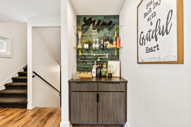 bar with dark brown cabinets and light hardwood / wood-style flooring