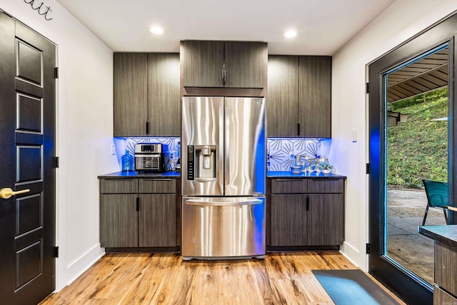 kitchen featuring stainless steel refrigerator with ice dispenser, light hardwood / wood-style floors, dark brown cabinetry, and tasteful backsplash