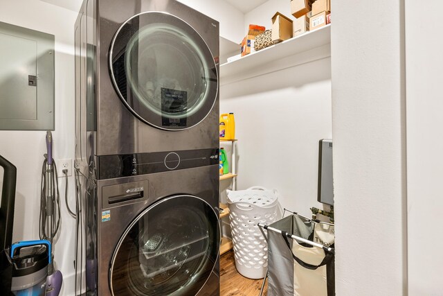 laundry room with stacked washer / dryer, electric panel, and hardwood / wood-style flooring