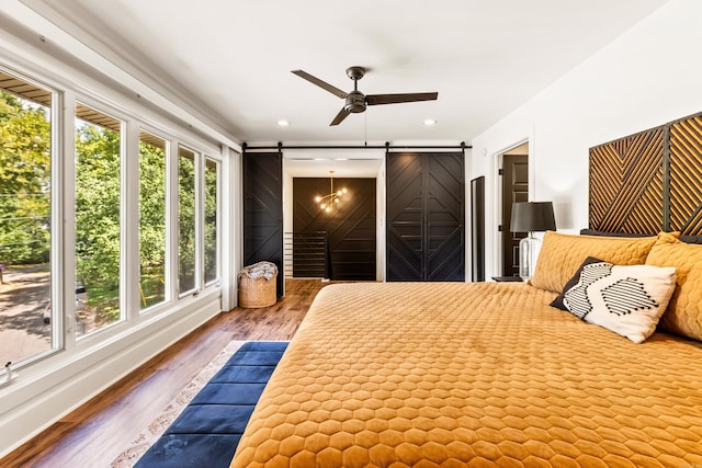 unfurnished bedroom featuring ceiling fan, hardwood / wood-style floors, and a barn door