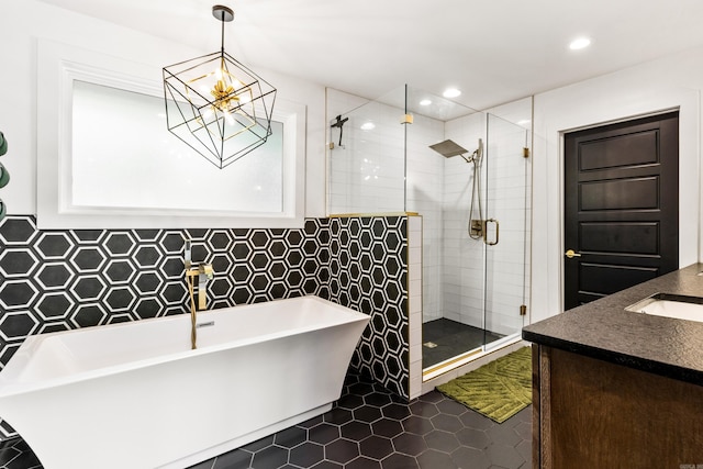 bathroom with tile walls, vanity, plus walk in shower, a chandelier, and tile patterned floors