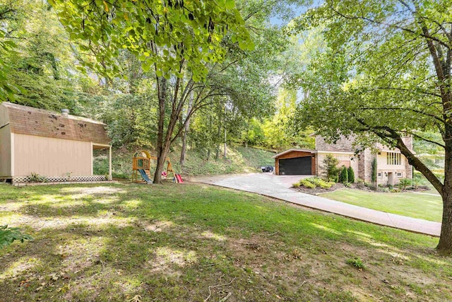 view of yard featuring a playground, a garage, and an outbuilding