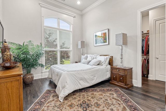 bedroom with dark hardwood / wood-style floors, ornamental molding, a spacious closet, and a closet